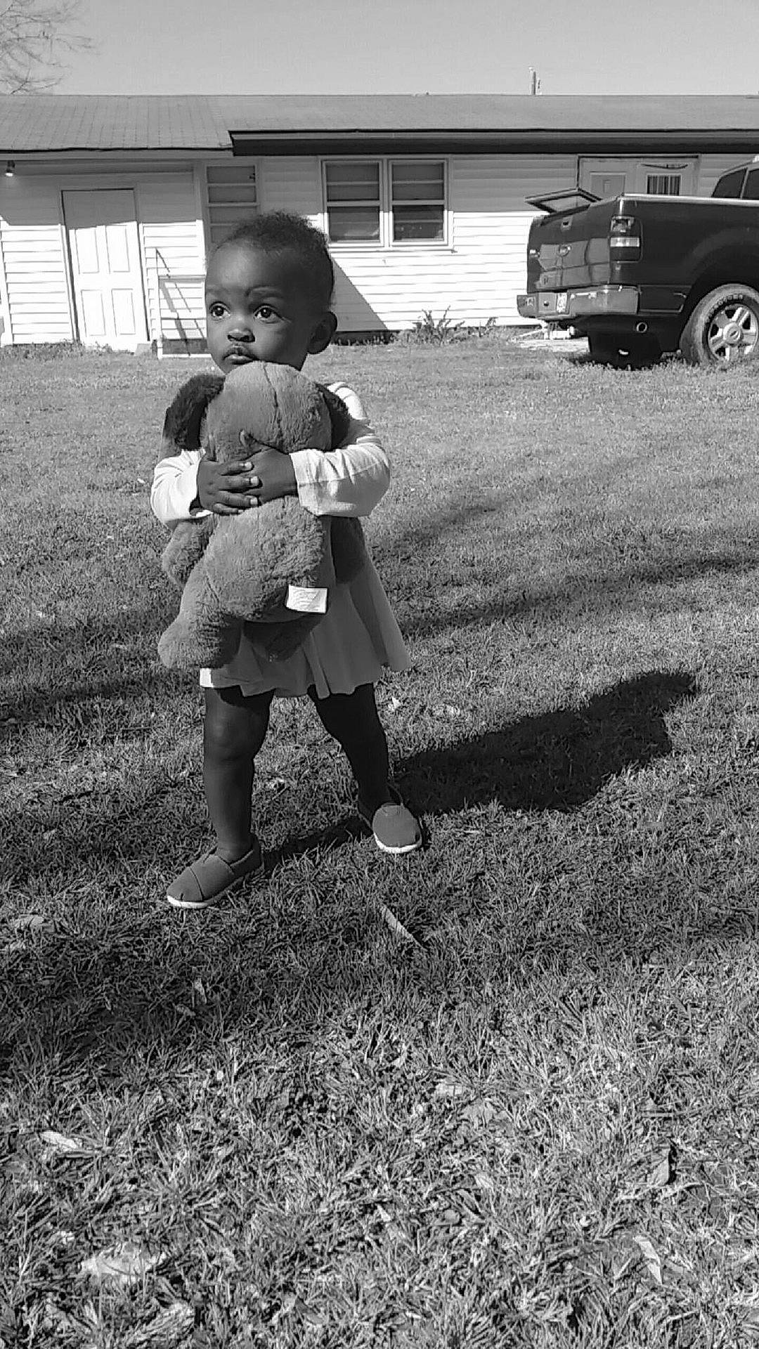 Taniyah is registered to the contest to win money with this photo: black, black_and_white, car, child, girl, grass, human_behavior, monochrome, monochrome_photography, person, photograph, photography, sitting, snapshot, standing, style, toddler, tree, white