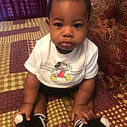 Justen joined the competition — help win amazing prizes! baby, child, infant, mickey_mouse, bib, socks, bedspread, patterned, indoor, portrait, person, cute, young, seated, small, black_hair, hands, feet, expression, clothing