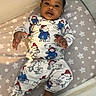 baby, infant, pajamas, crib, mattress, stars_pattern, cartoon_characters, sleepwear, child, cute, relaxed, indoor, person, face, hand, foot, textile, pattern, bed, sleeping_area
