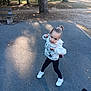 Chloé participe au concours pour gagner de l'argent avec cette photo : child, park, outdoor, hoodie, sneakers, pavement, trees, bench, sunlight, playful_pose, young_girl, casual_clothing, hair_bun, daytime, nature, person, fashion, expression, sidewalk, recreation