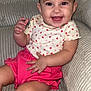 toddler, child, smiling, happy, hair_clip, pink_shorts, heart_pattern, shirt, couch, indoors, baby, cute, sitting, portrait, face, skin, hand, furniture, clothing, expression