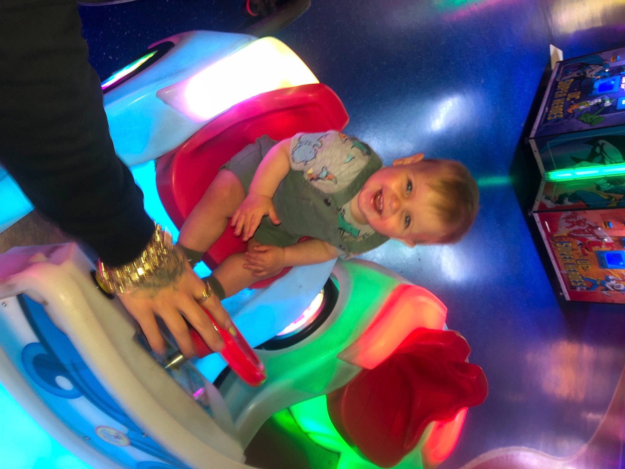 Arlo is registered to the contest to win money with this photo: arcade_game, baby, child, electric_blue, entertainment, event, fun, games, green, hat, indoor_games_and_sports, joy, leisure, light, lighting, magenta, person, play, recreation, recreation_room