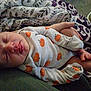 Noelle is registered to the contest to win money with this photo: baby, sleeping, infant, onesie, pumpkin, pattern, blanket, hand, foot, cozy, cute, child, clothing, comfort, rest, soft, person, indoor, closeup, toddler