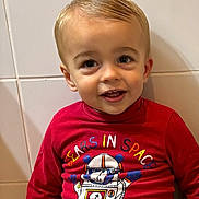 Mathias participe au concours pour gagner de l'argent avec cette photo : toddler, child, smiling, red_shirt, graphic_tshirt, astronaut_bear, indoor, portrait, face, happy, blonde_hair, short_hair, cute, sitting, casual_clothing, young_child, person, tile_wall, playful, bright_colors