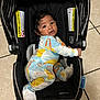baby, black, car_seat, child, colorful_clothing, cute, expression, face, floor, footwear, hair, indoors, infant, looking_up, pajamas, portrait, seat, small_person, tile, warning_label