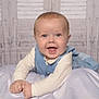 baby, background, blanket, blue_vest, child, clothing, cream_shirt, cute, face, happy, indoors, infant, lying_down, person, portrait, smiling, soft_lighting, studio_photo, toddler, wooden_wall
