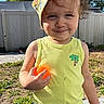 toddler, child, outdoor, sunny, hat, bucket_hat, yellow_tank_top, orange_ball, smile, grass, sidewalk, summer, shorts, playful, person, daylight, shadows, tree, fence, happy