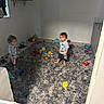 child, toddler, indoor, carpet, toy, pacifier, baby_gate, floor, room, furniture, clothing, barefoot, playtime, person, young_child, plush, matching_outfits, window, shelf, blank_wall