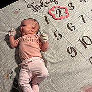 Annalee is registered to the contest to win money with this photo: baby, infant, blanket, milestone, numbers, pink, clothing, mittens, pacifier, lying_down, cute, portrait, child, floor, fabric, soft_lighting, decorative, floral_pattern, baby_girl, celebration