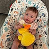 Annalee is registered to the contest to win money with this photo: baby, child, plush_toy, yellow_duck, baby_seat, patterned_fabric, indoor, curious, cute, infant, soft_toy, pink_clothing, sitting, face, person, young_child, toy, comfort, home, colorful