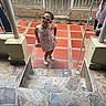 child, girl, toddler, sunglasses, dress, floral_pattern, sandals, standing, posing, smiling, outdoor, entrance, stairs, railing, tile, house, door, fashion, portrait, daylight