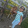 Antonella joined the competition — help win amazing prizes! child, cow, animal, outdoors, farm, petting_zoo, sunglasses, sun_hat, smiling, striped_shirt, light_blue_pants, sandals, wooden_fence, forest, trees, sunlight, portrait, standing, friendship, countryside