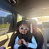 child, toddler, car, car_seat, sunglasses, smiling, passenger, seatbelt, sippy_cup, vehicle_interior, travel, sunlight, window, road, outdoor, portrait, fashion,  안전, family, daylight