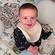 John joined the competition — help win amazing prizes! baby, child, balloon, bib, play_mat, smiling, happy, indoors, cute, young_child, clothing, face, hands, sitting, toy, pacifier, colorful, decor, balloons, infant