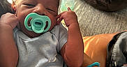 Mariyon is registered to the contest to win money with this photo: newborn, baby, infant, child, pacifier, sleepy, portrait, face, hands, stretching, onesie, couch, blanket, cushion, indoor, home, sitting, adult_arm, soft_lighting, family