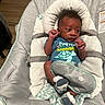 baby, infant, child, portrait, bouncer, baby_seat, indoor, sitting, lying_down, face, eyes_open, hands, turtle_shirt, socks, blanket, cushion, safety_harness, furniture, home, photography