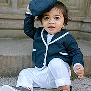 Krishiv joined the competition — help win amazing prizes! toddler, child, baby, blue_clothing, white_pants, navy_cap, sneakers, sitting, outdoor, stone_background, curly_hair, cute, playful, portrait, happy, person, casual, young_child, smiling, fashion