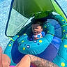 Ma'Kari is registered to the contest to win money with this photo: arm, baby, blue, canopy, child, float, green, infant, inflatable, outdoor, pool, protective, relaxed, sitting, summer, sunlight, swimming, tattoo, vacation, water