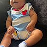 baby, child, clothing, couch, curly_hair, cute, furniture, happy, head, indoor, infant, mickey_mouse, onesie, person, portrait, sitting, skin, smiling, white_socks, young