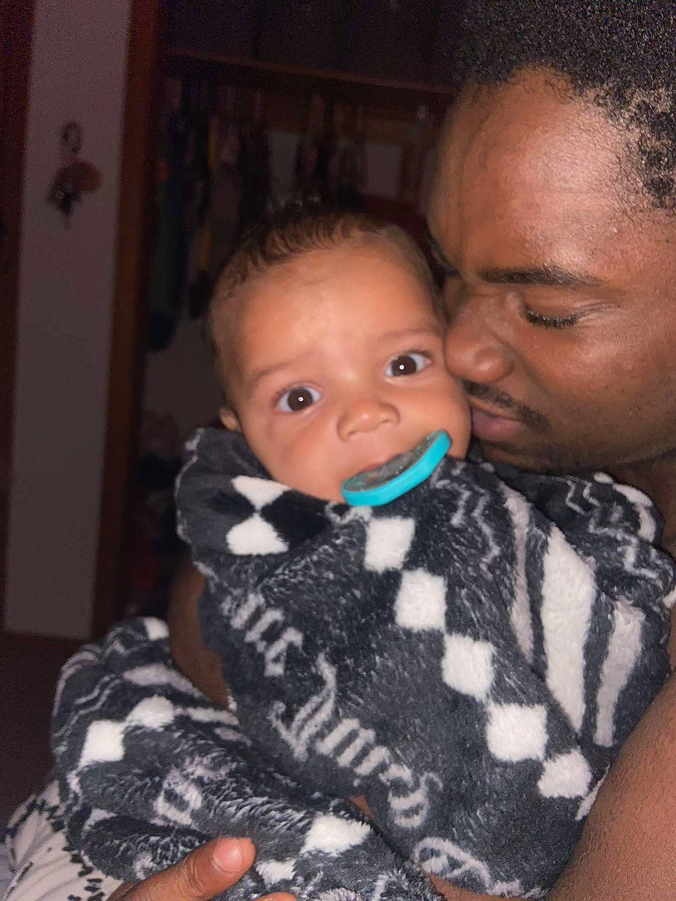 Legend is registered to the contest to win money with this photo: arm, baby, baby_toddler_clothing, black_hair, cheek, chin, comfort, ear, eyebrow, eyelash, forehead, happy, hug, iris, lip, mouth, nose, pattern, person, skin