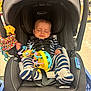 baby, infant, car_seat, graco, striped_clothing, sleeping, toy, colorful_toy, child, shopping_cart, store, seatbelt, baby_clothes, footwear, headrest, indoor, floor, person, cute, resting