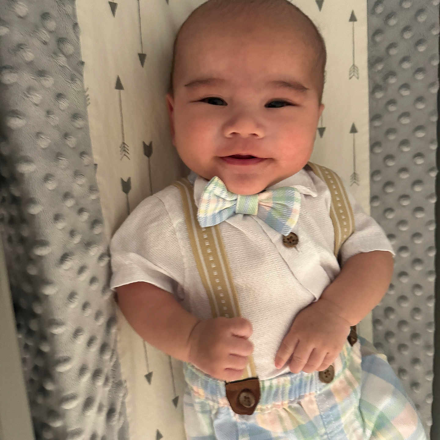 Anakin Lucas is registered to the contest to win money with this photo: arrow_pattern, baby, bedding, bow_tie, child, clothing, crib, face, hands, happy, indoors, infant, lying_down, nursery, outfit, plaid, portrait, smiling, soft_blanket, suspenders