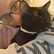 Zackary Binks is registered to the contest to win money with this photo: person, cat, black_cat, glasses, collar, sleeping_cat, close_up, indoor, cozy, hug, smile, face, eyewear, apparel, cuddle, pet, comfort, portrait, resting, warmth