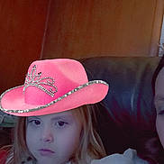 Tayler joined the competition — help win amazing prizes! child, girl, face, pink_hat, hat_filter, couch, sofa, living_room, wood_paneling, wall, portrait, selfie, filter_effect, sparkles, bored_expression, long_hair, holiday_clothing, indoor, low_light, person