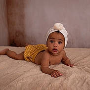 Emy a rejoint le concours — aidez-le/la à gagner de superbes lots ! baby, infant, child, blanket, bedroom, turban, headwear, polka_dot, yellow_shorts, skin, cute, expression, lying_down, indoors, portrait, soft_texture, young, looking, hand, face