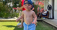 Sawyer is registered to the contest to win money with this photo: adults, backyard, beanbag, blue_clogs, blue_hat, blue_shorts, child, cornhole, game_board, grass, house, outdoor, porch, portrait, shirtless, smiling, standing, summer, toddler, trees