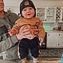 Sawyer is registered to the contest to win money with this photo: baby, child, smiling, cap, adult_hand, kitchen, counter, cabinet, clothing, footwear, indoor, person, happy, face, holding, table, decor, appliance, portrait, casual