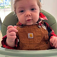 Bryson is registered to the contest to win money with this photo: baby, child, high_chair, overalls, plaid_shirt, indoor, face, cute, young_child, clothing, person, portrait, hand, curious, messy_hair, infant, seat, looking_at_camera, toddler, casual