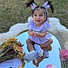 Kaia is registered to the contest to win money with this photo: baby, child, girl, pigtails, hair_clips, purple_dress, white_shoes, smiling, outdoor, grass, flowers, cake, storybook, reflection, mirror, portrait, cute, happy, sitting, celebration
