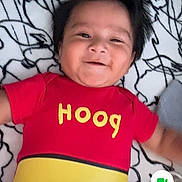 Gael Alexander is registered to the contest to win money with this photo: baby, infant, child, smiling, lying_down, portrait, red_clothing, yellow_clothing, onesie, blanket, bed, indoors, phone_screenshot, video_call, face, hair, happy, patterned_background, casual_photo, close_up