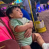 baby, child, infant, portrait, sitting, stroller, night, outdoor, carnival, fairground, lights, colorful, curious, smiling, green_clothing, striped_shirt, white_sock, shopping_bag, street, family