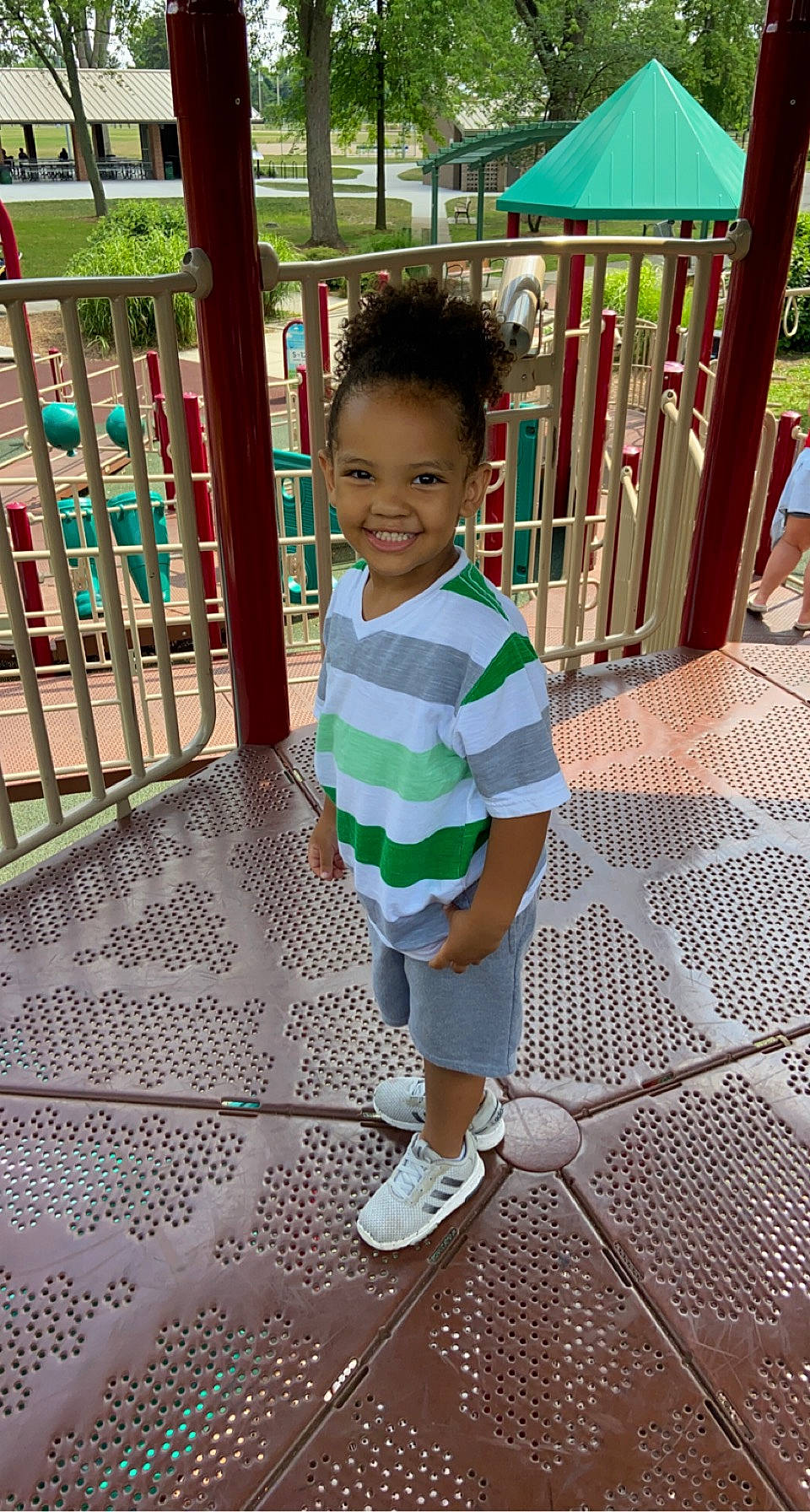 Justus is registered to the contest to win money with this photo: baby_toddler_clothing, child, city, flooring, fun, grass, happy, joy, leisure, outdoor_play_equipment, pattern, person, play, playground, public_space, recreation, shorts, sleeve, smile, standing