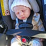 baby, sleeping, car_seat, child, infant, knit_hat, pajamas, safety_harness, seatbelt, hand, face, peaceful, indoors, sunlight, closeup, cute, child_safety, transportation, car_interior, resting