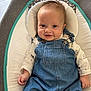 baby, baby_rocker, blue_clothing, child, clothing, cushion, cute, dog_prints, face, happy, indoor, infant, light_skin, overalls, portrait, seated, short_hair, small_hands, smile, white_shirt