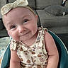 Peyton joined the competition — help win amazing prizes! baby, child, infant, smiling, headband, bow, floral_clothing, sitting, baby_seat, couch, living_room, pillow, cute, portrait, indoors, skin, face, person, happy, young