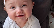 Peyton is registered to the contest to win money with this photo: baby, child, pink_headband, smile, white_onesie, cushion, indoor, face, infant, cute, happy, portrait, sitting, headwear, childhood, apparel, young_child, soft_lighting, closeup, baby_girl