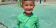 Colson joined the competition — help win amazing prizes! child, boy, swimwear, pool, water, splash_pad, toy, smile, outdoor, summer, recreation, play, water_spray, green_shirt, dinosaur, park, people, sunny, fun, happy