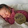 Winslow is registered to the contest to win money with this photo: baby, infant, sleeping, one_month, purple_outfit, blanket, soft_texture, smile, newborn, portrait, cozy, cute, peaceful, wooden_sign, milestone, resting, child, indoor, toddler, face