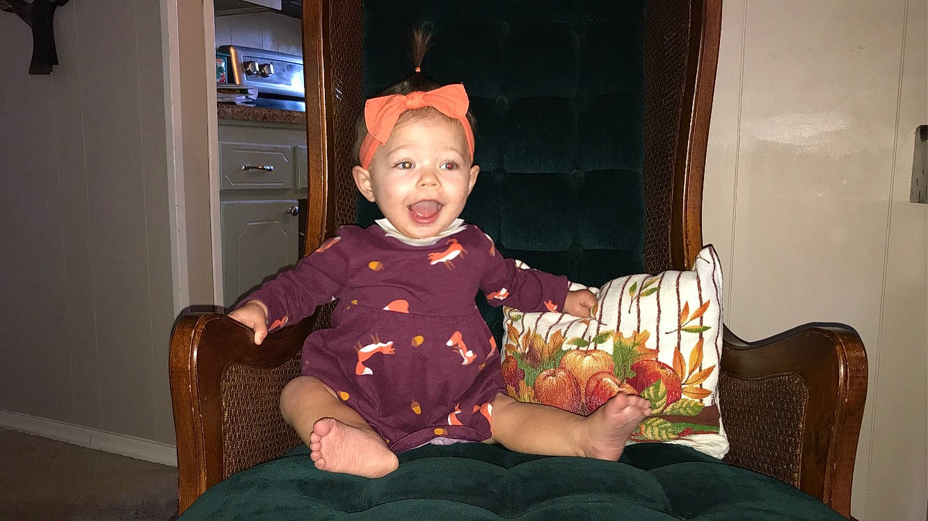 Lynlee is registered to the contest to win money with this photo: baby, baby_toddler_clothing, chair, child, comfort, door, event, fun, furniture, happy, hat, lap, person, plant, room, sitting, sleeve, smile, t_shirt, television