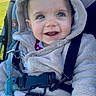 baby, blanket, blue_eyes, buckle, child, cozy, cute, eyelashes, grass, harness, hood, jacket, outdoors, pacifier, portrait, sitting, smile, stroller, toy, winter_clothing