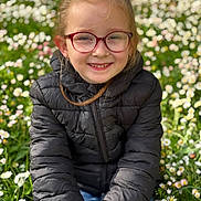 Emmy a rejoint le concours — aidez-le/la à gagner de superbes lots ! black_jacket, casual, child, cute, daylight, field, flowers, girl, glasses, grass, greenery, hair, happy, nature, outdoor, portrait, sitting, smiling, spring, young