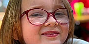 Emmy a rejoint le concours — aidez-le/la à gagner de superbes lots ! arms, blurred_background, casual, child, daylight, face, glasses, hair, happy, head, nature, outdoor, person, portrait, red_glasses, resting, skin, smile, table, young