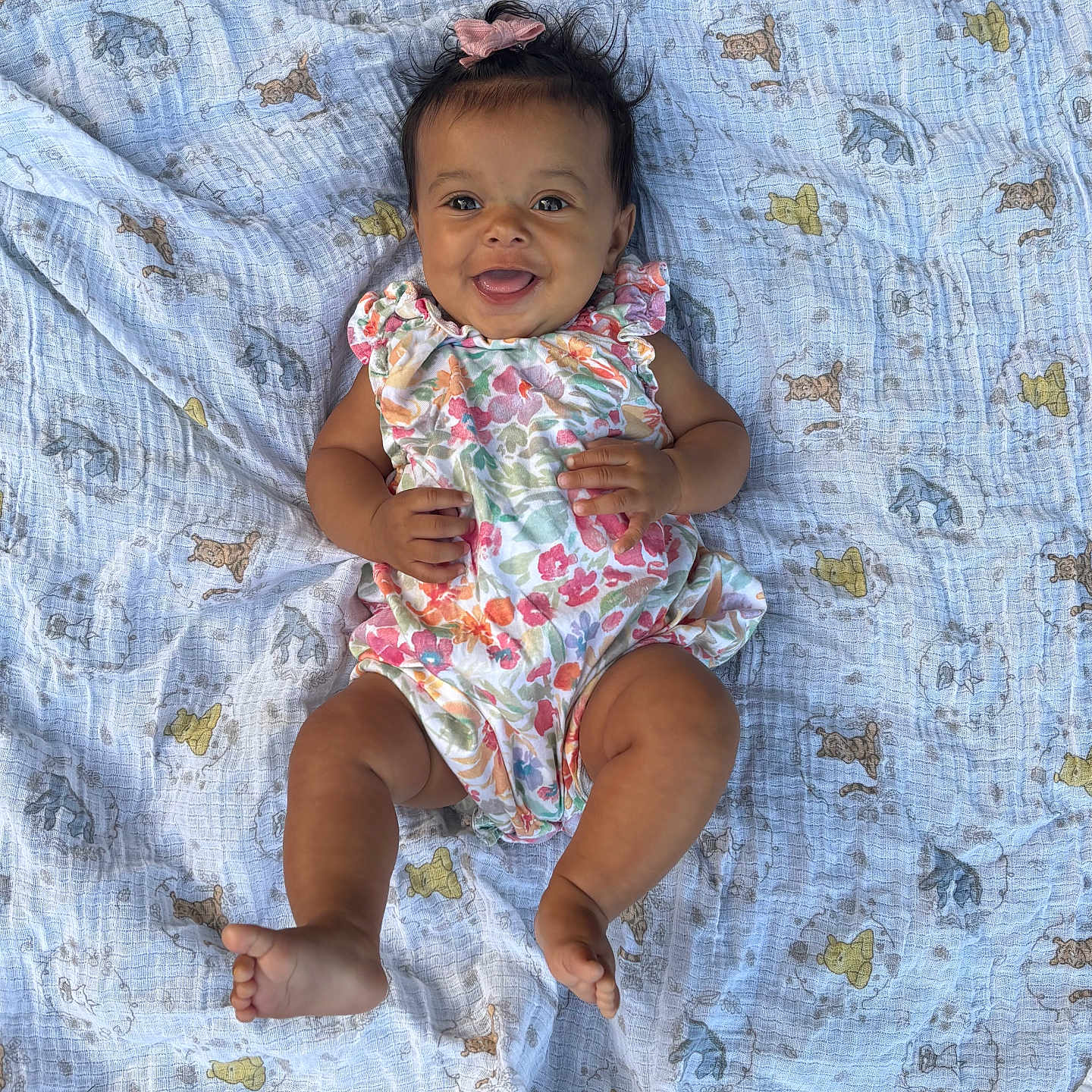 Lyvia is registered to the contest to win money with this photo: baby, child, smiling, happy, infant, blanket, pattern, animal_print, floral_outfit, pink_bow, lying_down, cute, portrait, skin, hand, foot, indoors, soft_texture, colorful, person