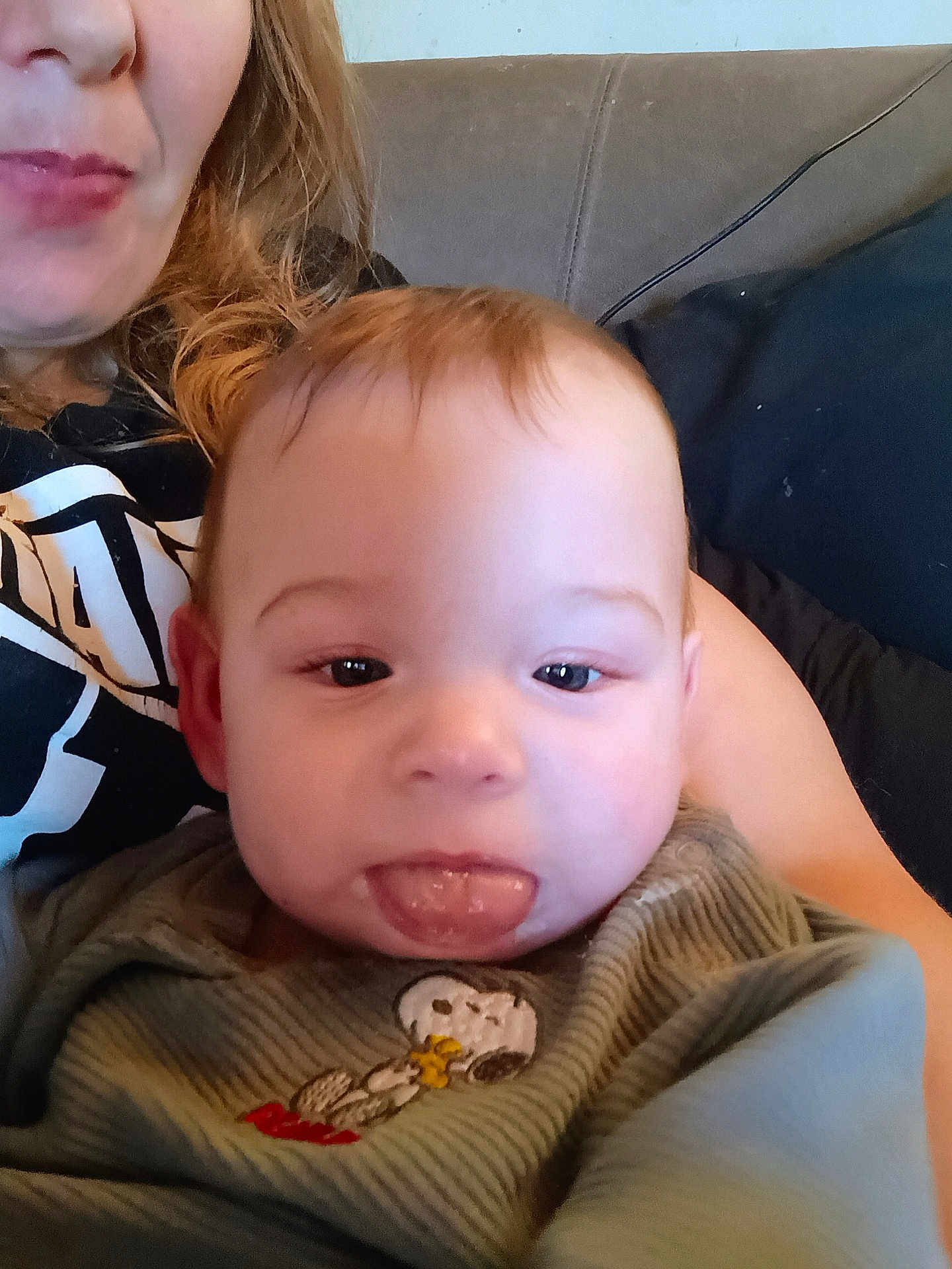 Oliver joined the competition — help win amazing prizes! baby, tongue, face, child, person, adult, clothing, indoor, sofa, couch, hair, sitting, smiling, cute, playful, expression, closeup, portrait, snoopy, green