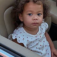 Gianna joined the competition — help win amazing prizes! child, toddler, car_seat, curly_hair, white_dress, ladybug_print, portrait, indoor, seat, car, person, cute, young_child, expressionless, skin, face, sitting, clothing, hair, young