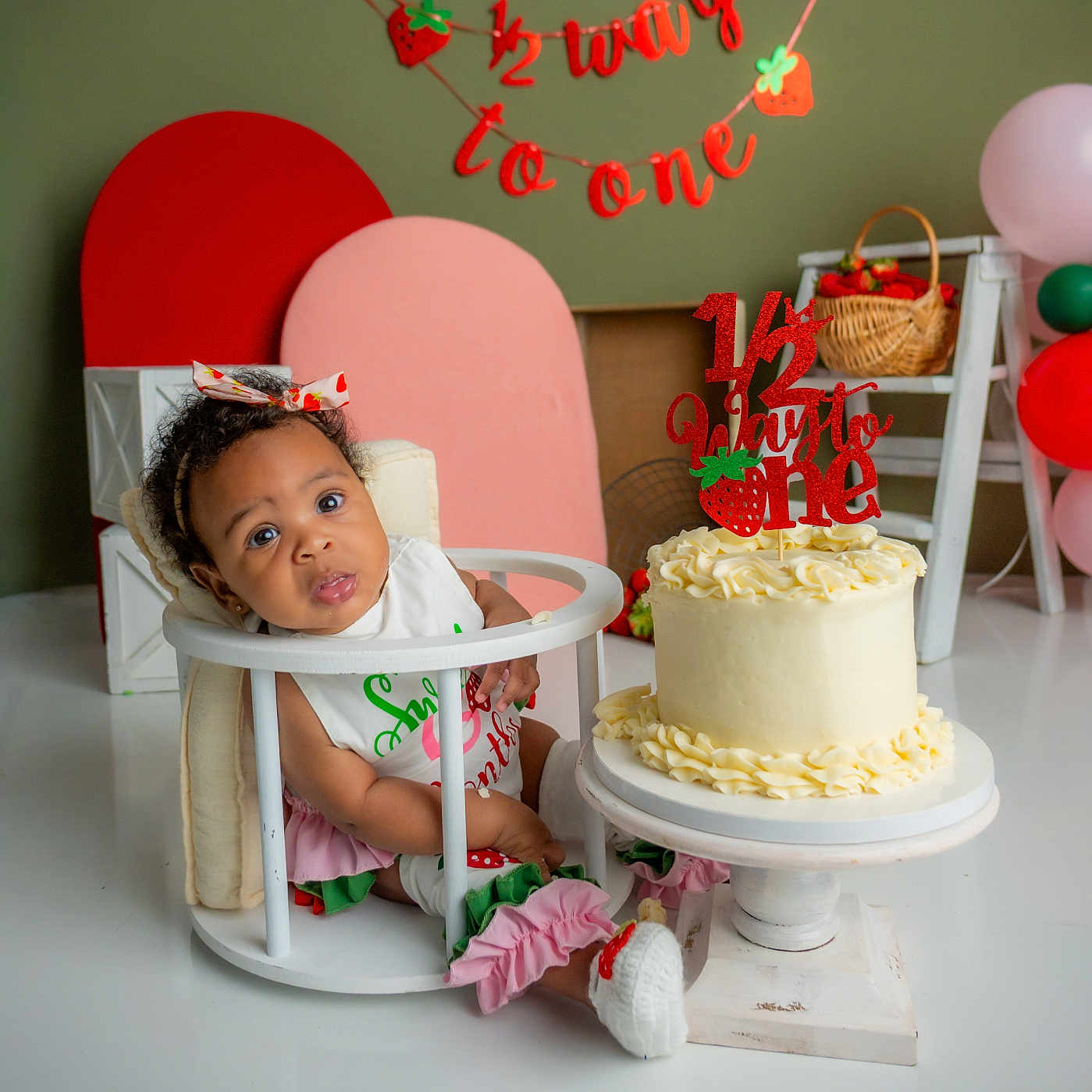 Delilah joined the competition — help win amazing prizes! baby, infant, highchair, cake, birthday, celebration, decorations, balloons, headband, bow, strawberry, basket, banner, white_floor, pink, red, green, cute, curious, festive